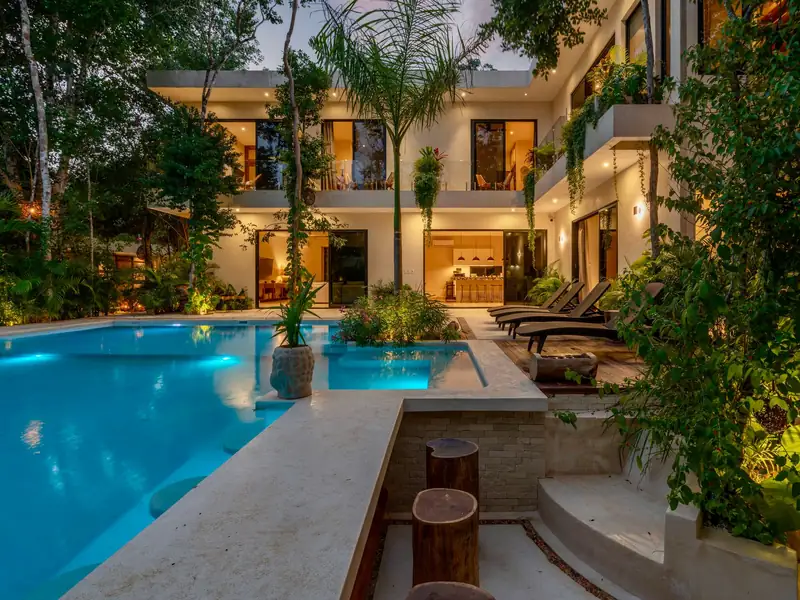 Piscina com iluminação automatizada ao entardecer em jardim tropical